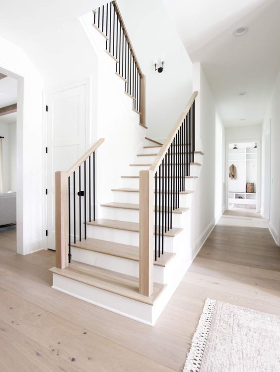 a white staircase with black railing and wooden handrails in a home hallway area