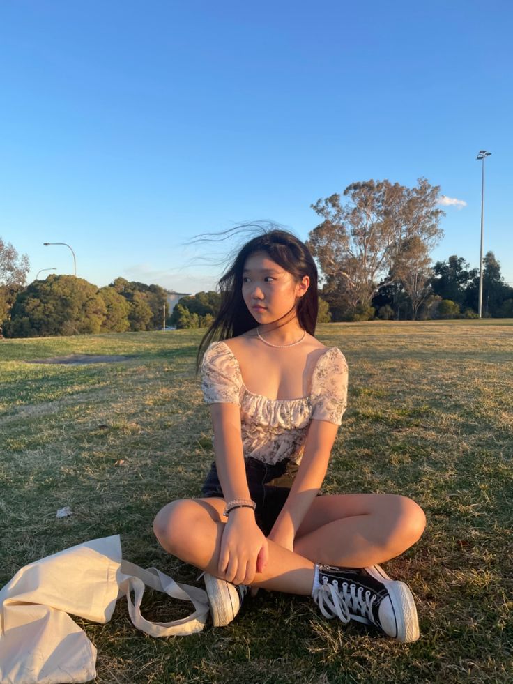 a young woman sitting on the ground with her legs crossed and shoes in front of her