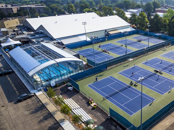 an aerial view of a tennis court with many people playing on it and buildings in the background