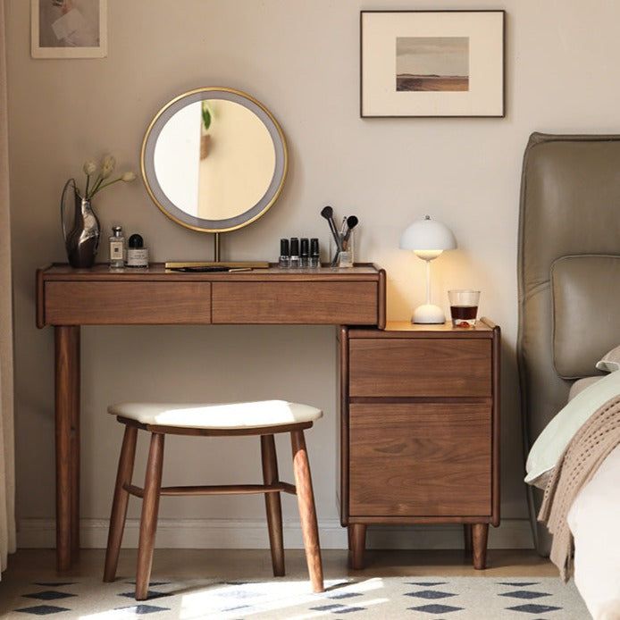 a bedroom with a bed, desk and mirror on it's side table in front of a window