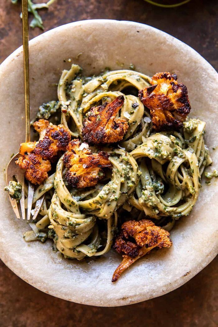 a bowl filled with pasta and shrimp on top of a wooden table next to a fork