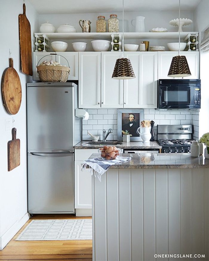 a kitchen with white cabinets and stainless steel appliances, including an island in the middle