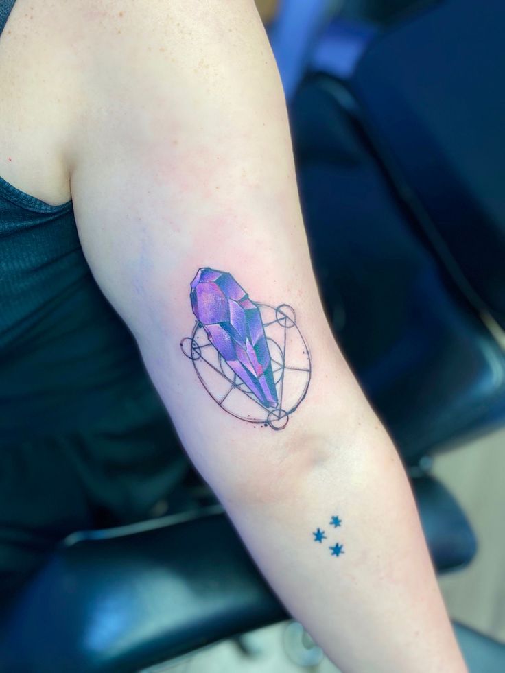 a woman's arm with a tattoo on it that has a purple diamond in the center