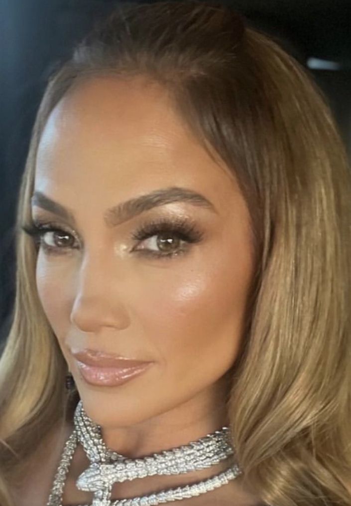 a woman with long blonde hair wearing a choker and jewelry on her neck, looking at the camera