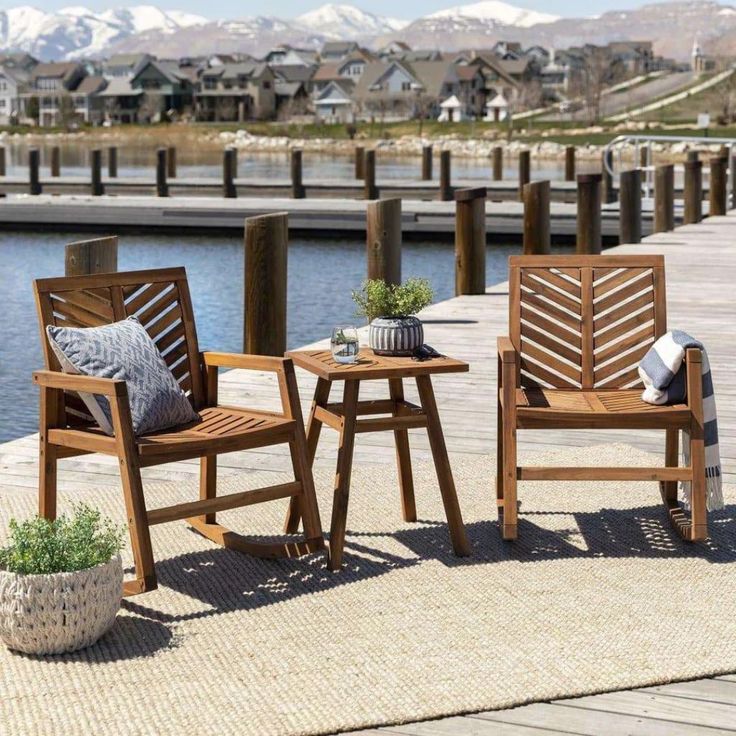 two wooden chairs sitting next to each other on a pier