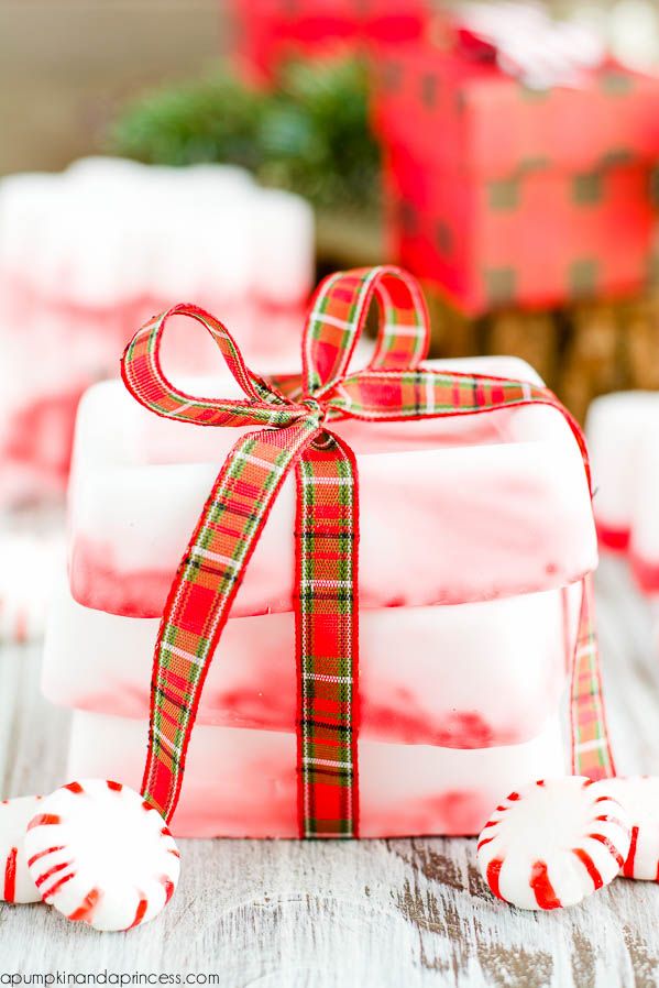 candy canes wrapped in red and white paper with a bow on top, sitting next to christmas candies