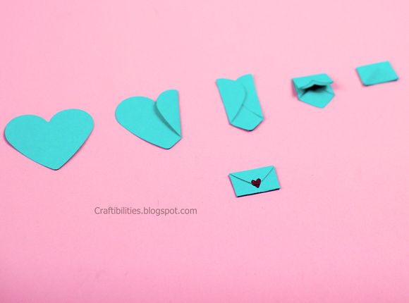 several pieces of blue paper with hearts cut out of them on a pink background,