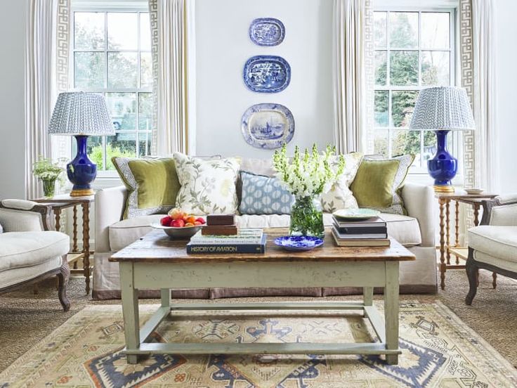 the living room is decorated in blue and white with plates on the wall above the coffee table