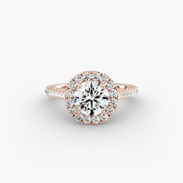 a rose gold engagement ring with round diamonds on the band and an halo setting in the center