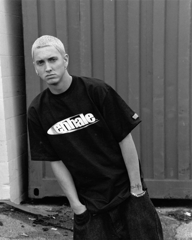 black and white photograph of a young man holding a skateboard in front of a building