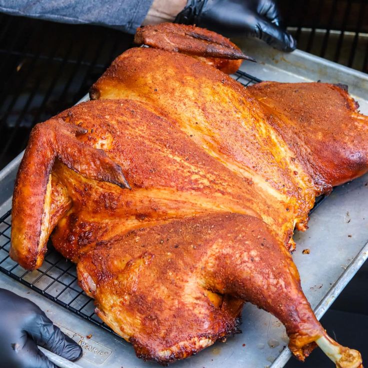 a roasting chicken is being cooked on a grill