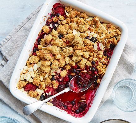 berry cobbler in a white baking dish with spoons and glasses on the side