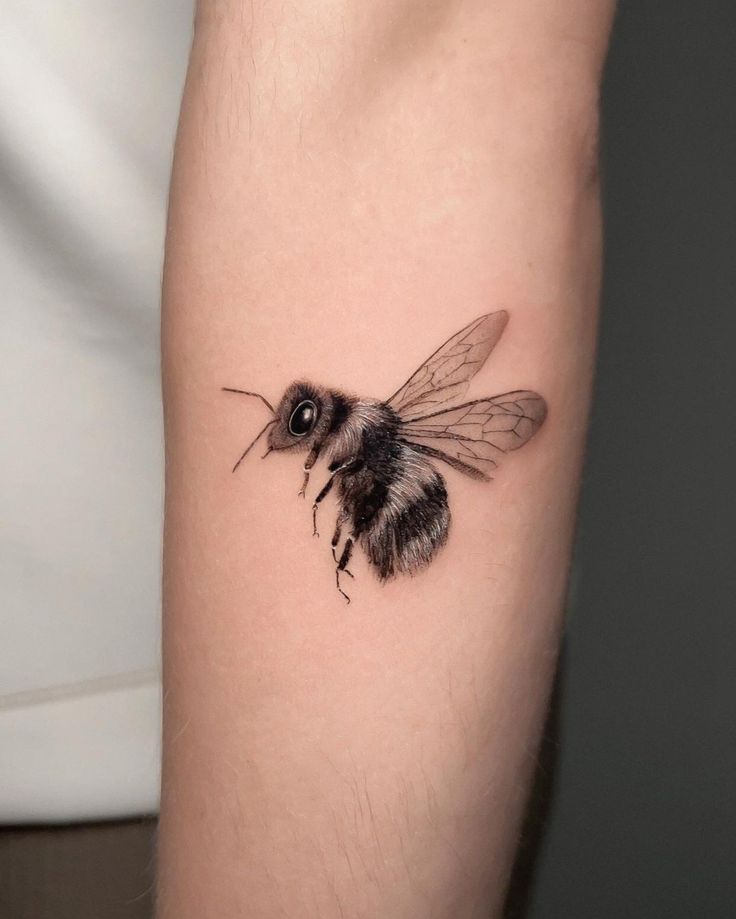 a small bee tattoo on the arm