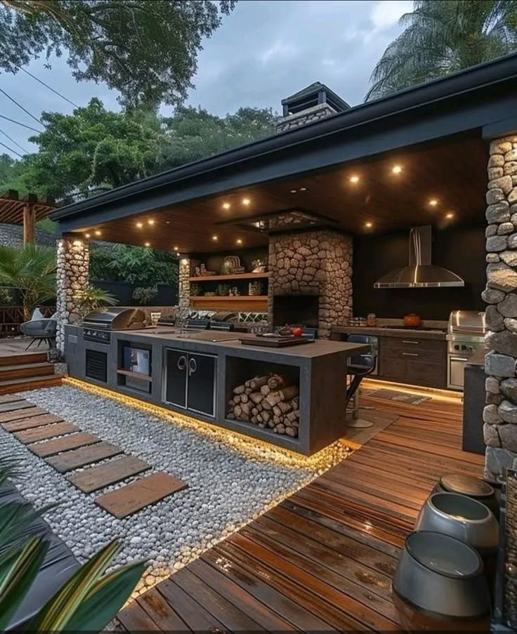 an outdoor kitchen is lit up at night with lights on the roof and wood flooring