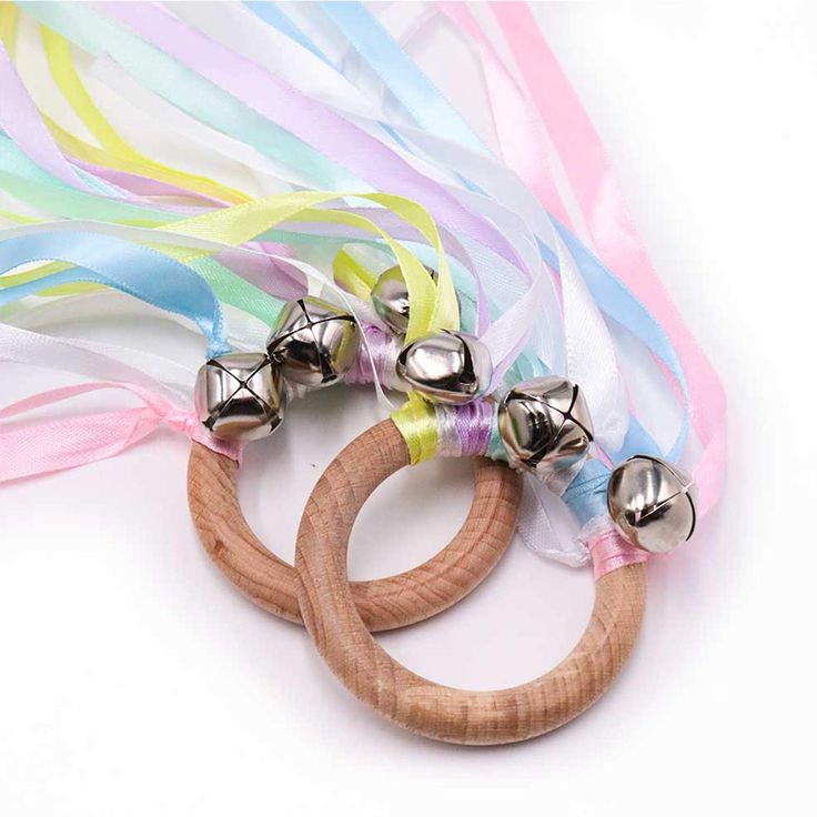 two wooden bracelets with bells on them and ribbons around the wristband, all in different colors