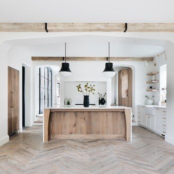 an open kitchen with herringbone flooring and white walls, along with wooden beams on the ceiling