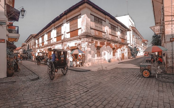 a horse drawn carriage driving down a cobblestone street in front of a tall building