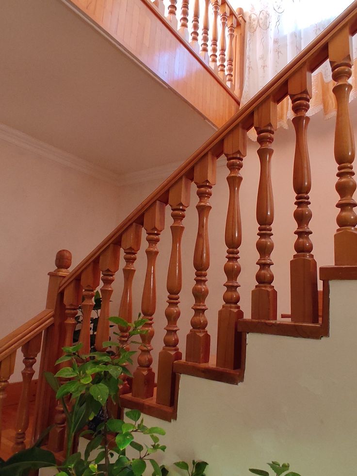 a wooden stair case next to a potted plant