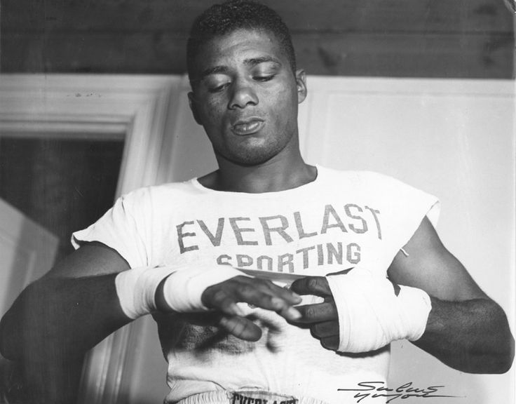 a black and white photo of a man with bandages on his hands holding something in one hand