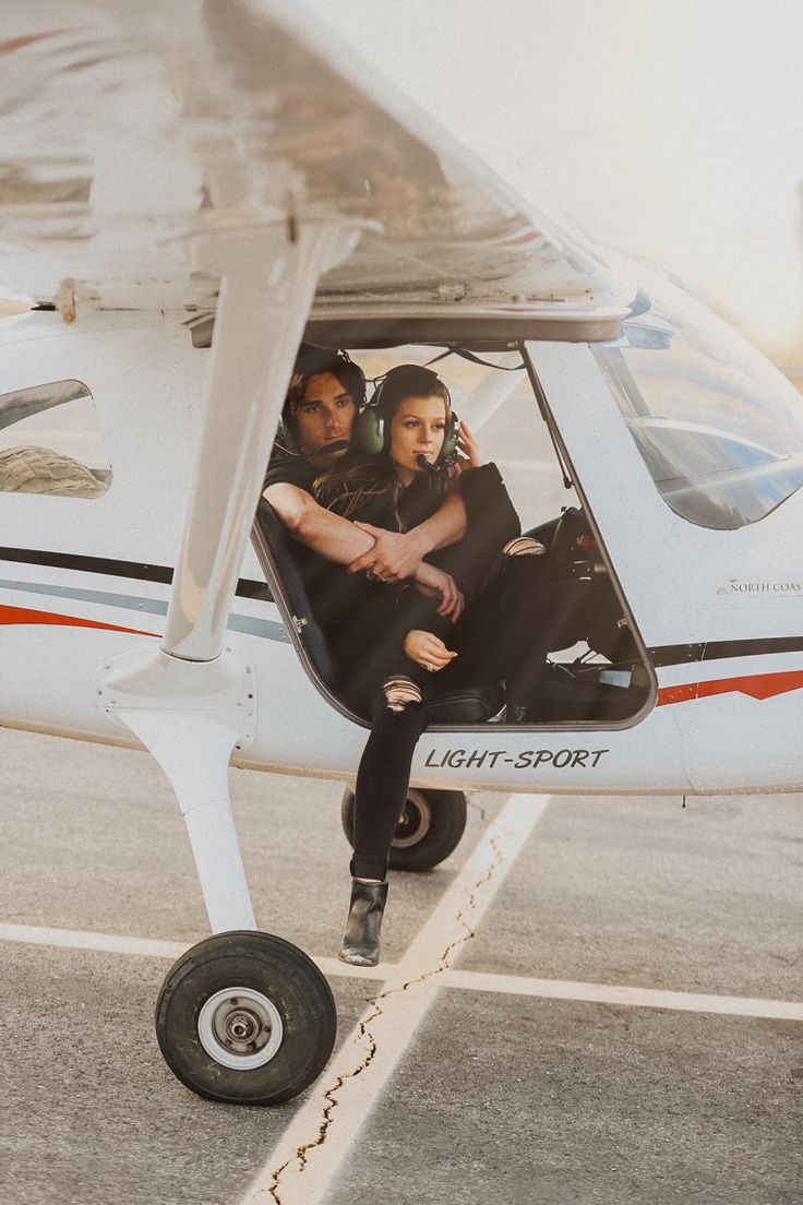 a man and woman sitting in the cockpit of a small plane with their arms around each other