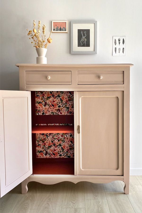 a white cabinet with drawers and pictures on the wall