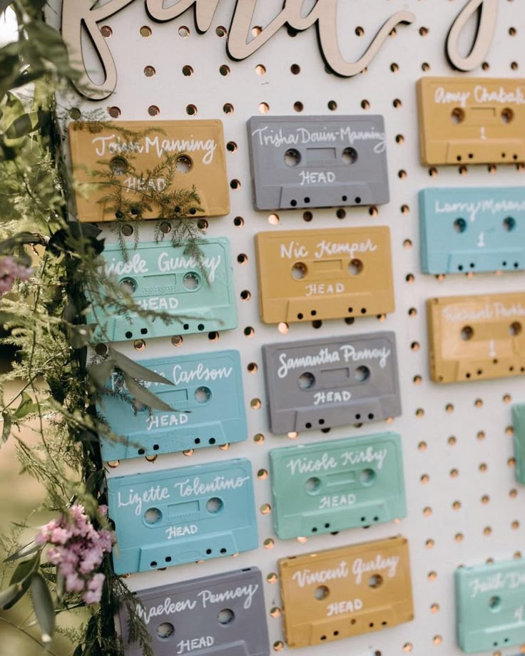 there are many cassettes on the wall with name tags attached to them and some flowers