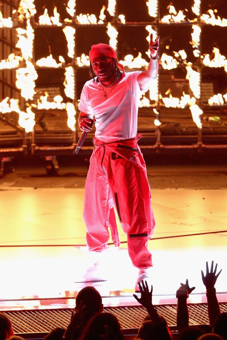 a man standing on top of a stage with his arms in the air while holding a microphone