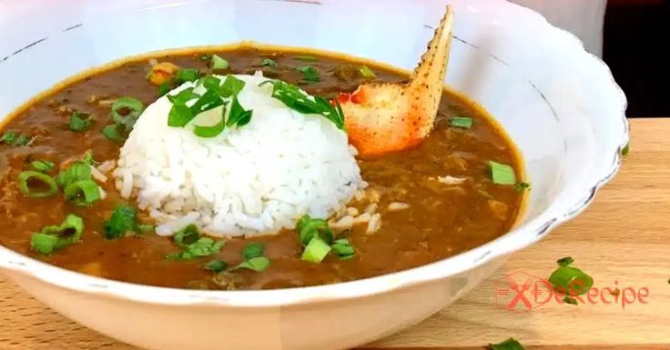 a bowl filled with soup and rice on top of a wooden table