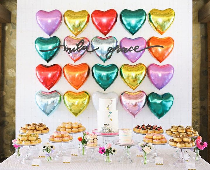 a table topped with lots of heart shaped balloons next to cakes and desserts on plates