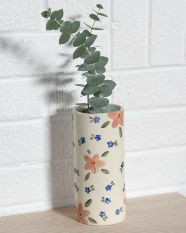 a plant in a ceramic vase on a wooden table next to a white brick wall