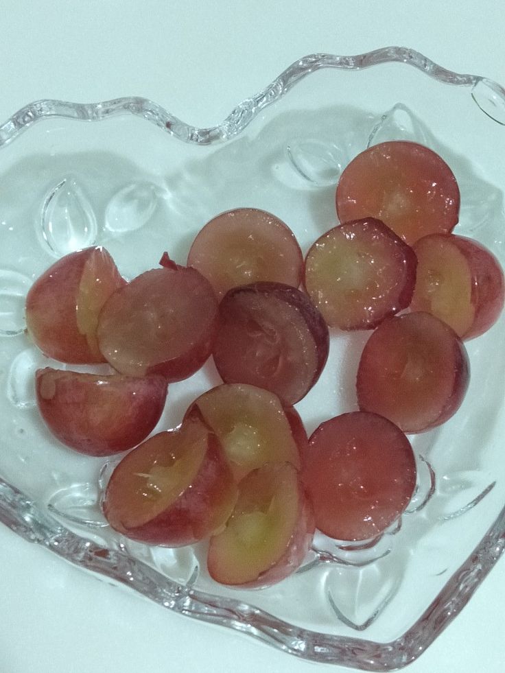 small pieces of fruit in a heart shaped glass bowl on a table top, ready to be eaten