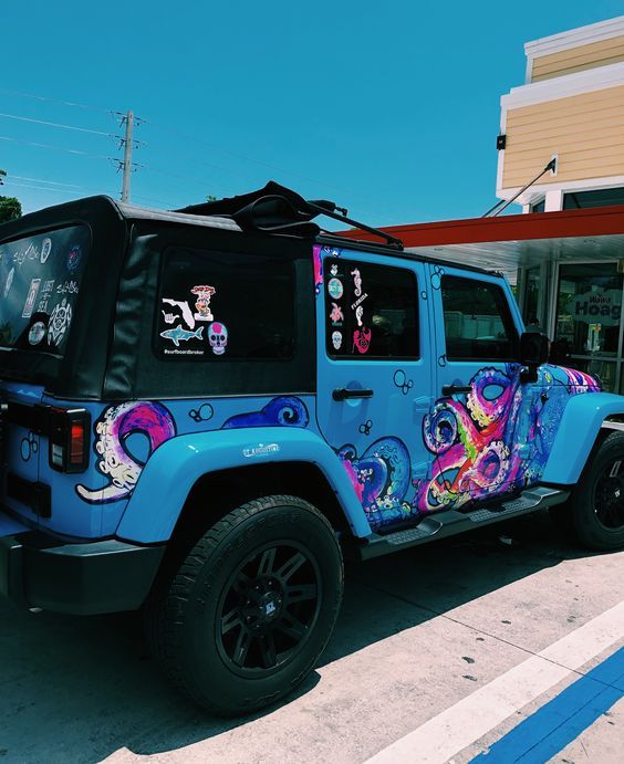 a blue jeep parked in front of a building with graffiti on it's side