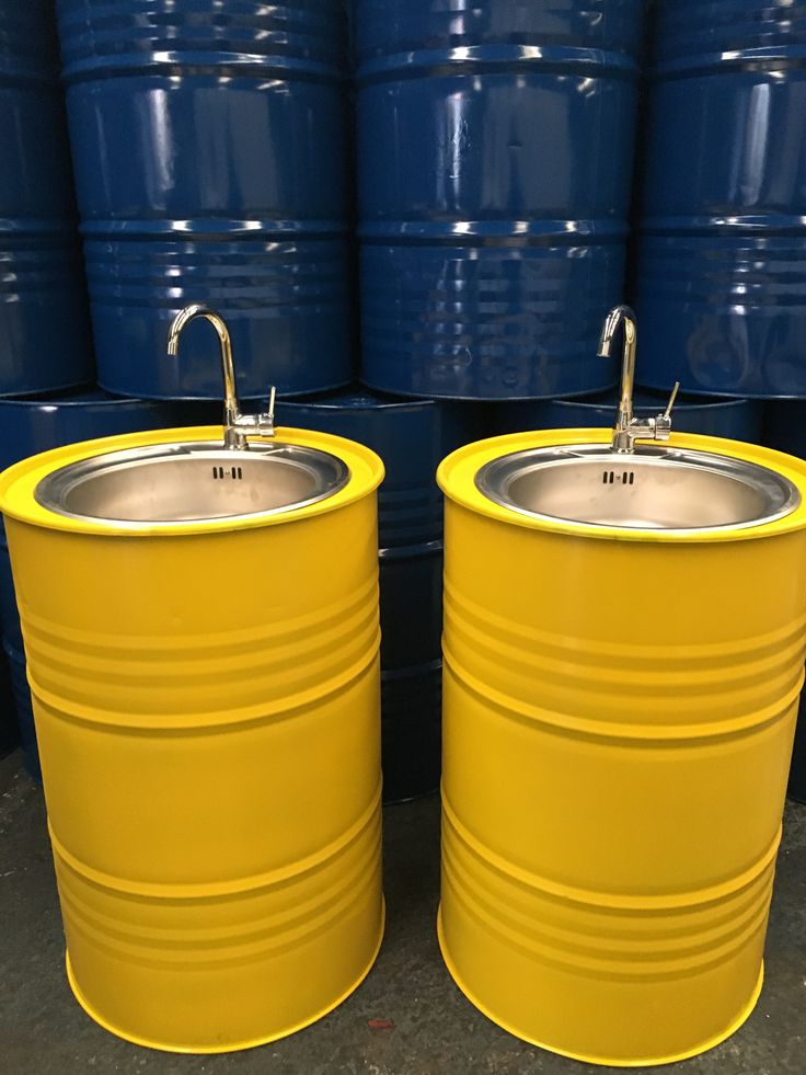 two large yellow barrels sitting next to each other in front of blue barrels with silver sinks