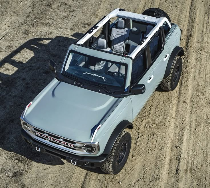 an off - road vehicle is parked in the dirt near some rocks and sand on a sunny day