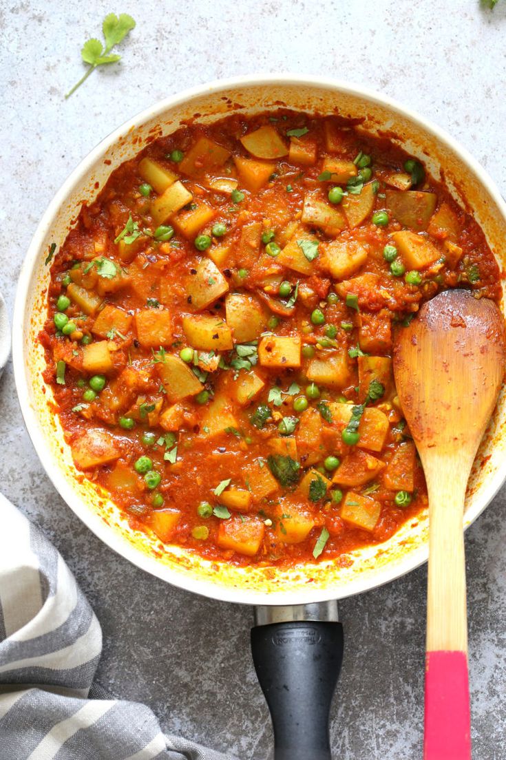 a pot filled with stew and a wooden spoon on top of the pot next to it