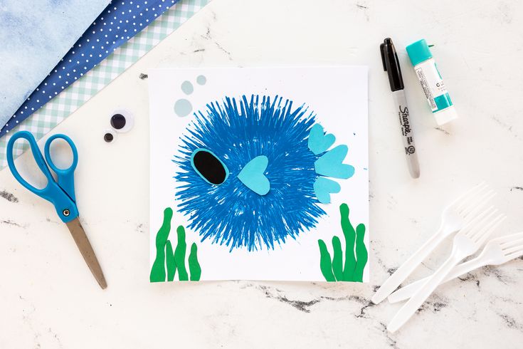 a card with an image of a blue porcupine on it next to scissors and markers