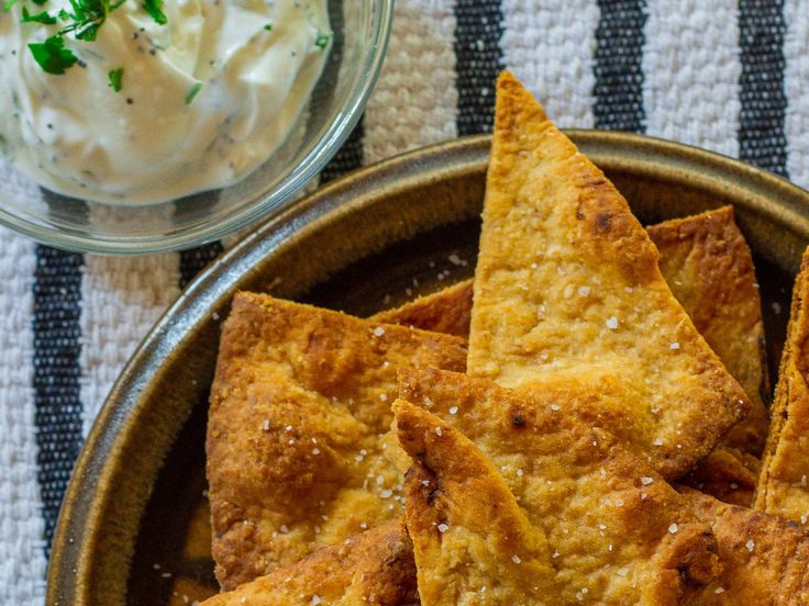 some tortilla chips are on a plate next to a bowl of sour cream