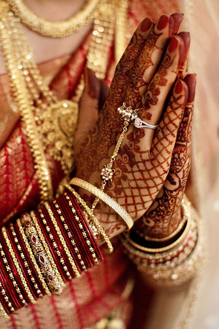 a woman with her hands covered in henna and bracelets, wearing gold jewelry