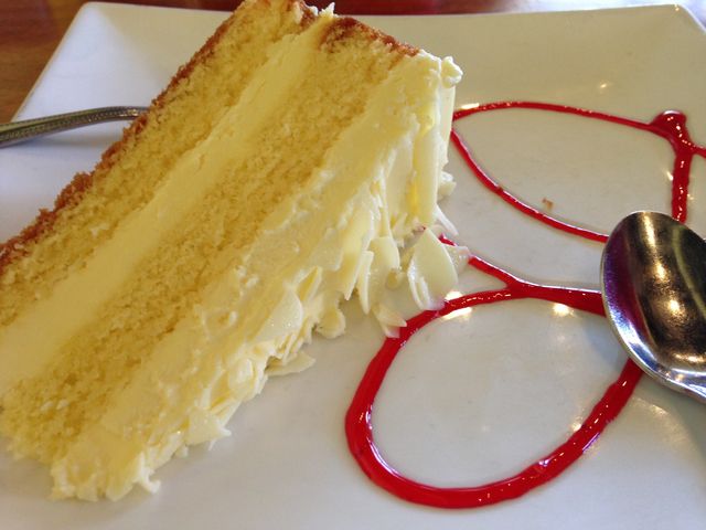 a piece of cake on a white plate with a red saucer next to it