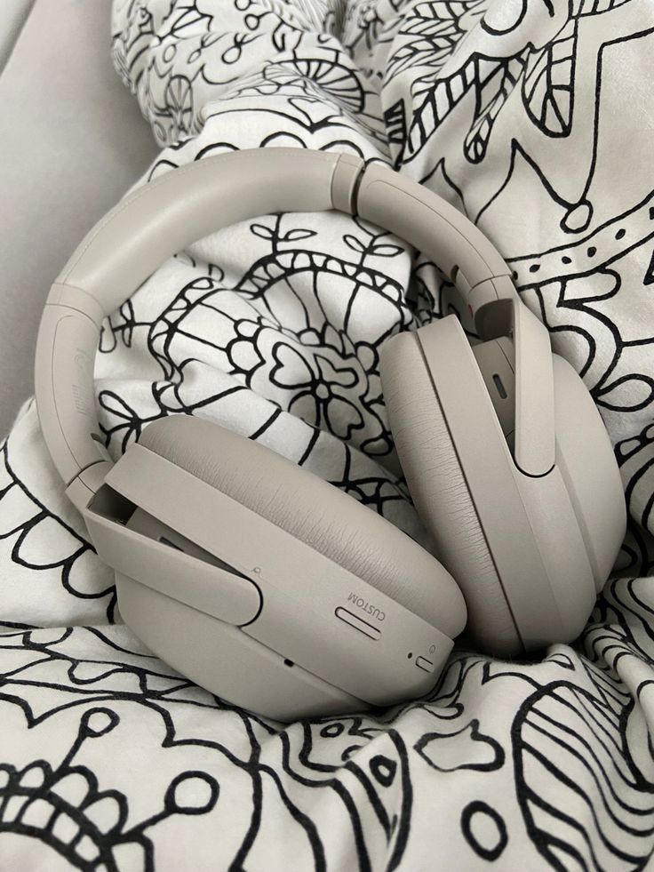 the headphones are laying on top of the bed sheet in front of the pillow