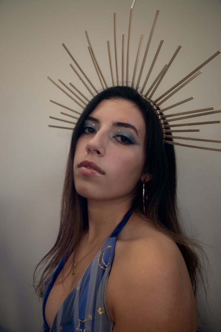 a woman with makeup on her face and sunburst headpiece in front of her