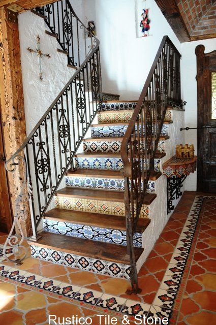 the stairs in this house are decorated with decorative tiles and wrought iron handrails