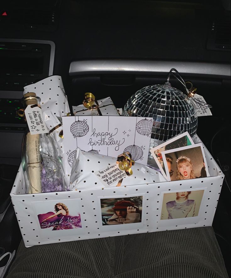 a white box filled with pictures and cards in the back of a car seat next to a disco ball