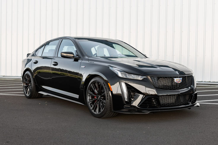 a black sports car parked in front of a white garage door with no doors on it