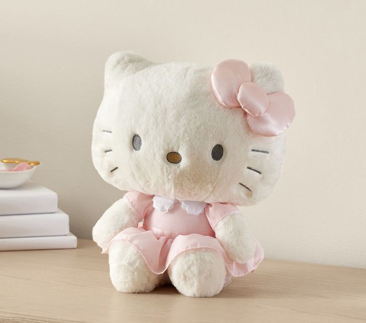 a hello kitty stuffed animal sitting on top of a wooden table next to some books