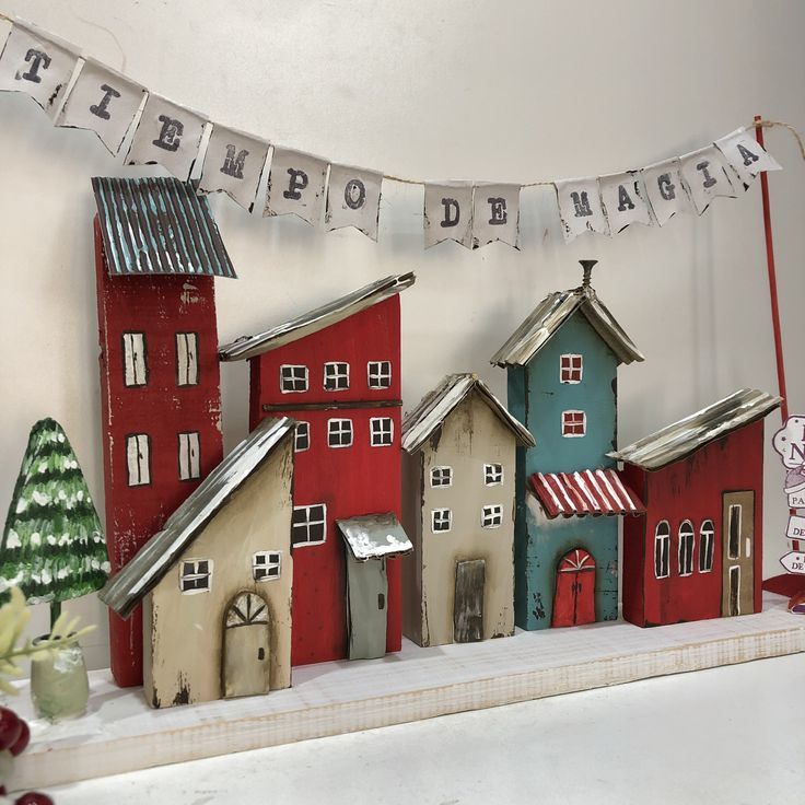 a group of small wooden houses sitting on top of a shelf next to a christmas tree