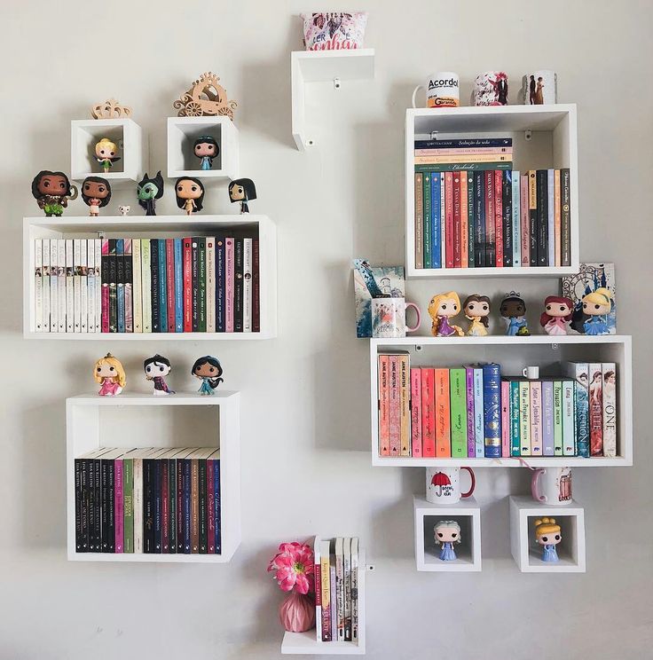 two white shelves filled with books and stuffed animals next to each other on the wall