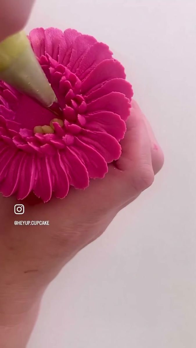 a person holding a pink flower in their left hand with a yellow tip sticking out of it