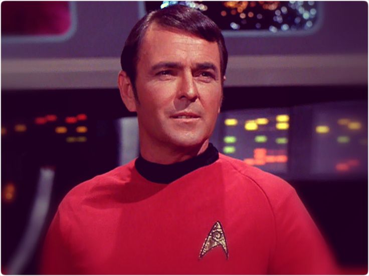 a man in a red uniform is looking at the camera while wearing a star trek shirt