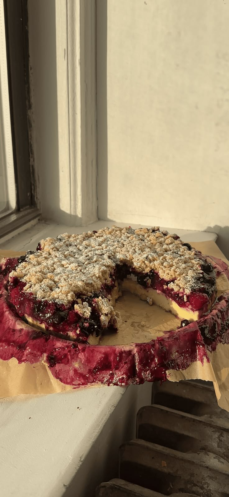 a pie sitting on top of a wooden table next to a window sill with a slice missing from it